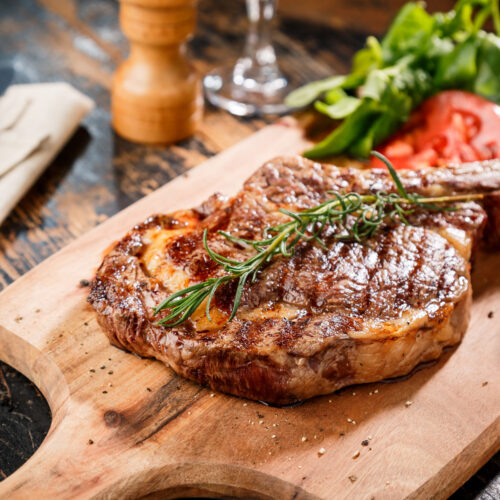 Indulge in Upscale Living - ribeye steak on a wooden chopping board with vegetables on the side